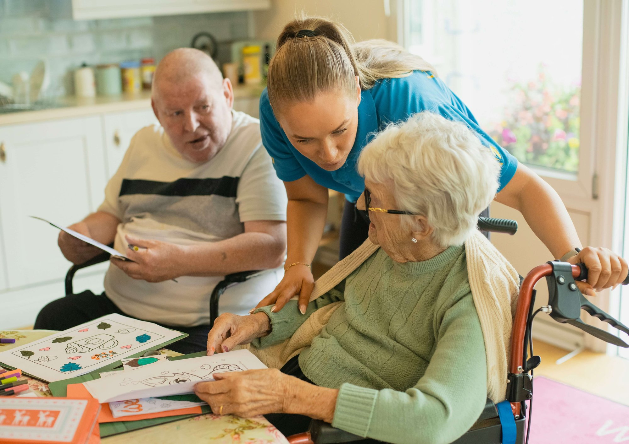 TLC staff member and an older man and woman in the activities room